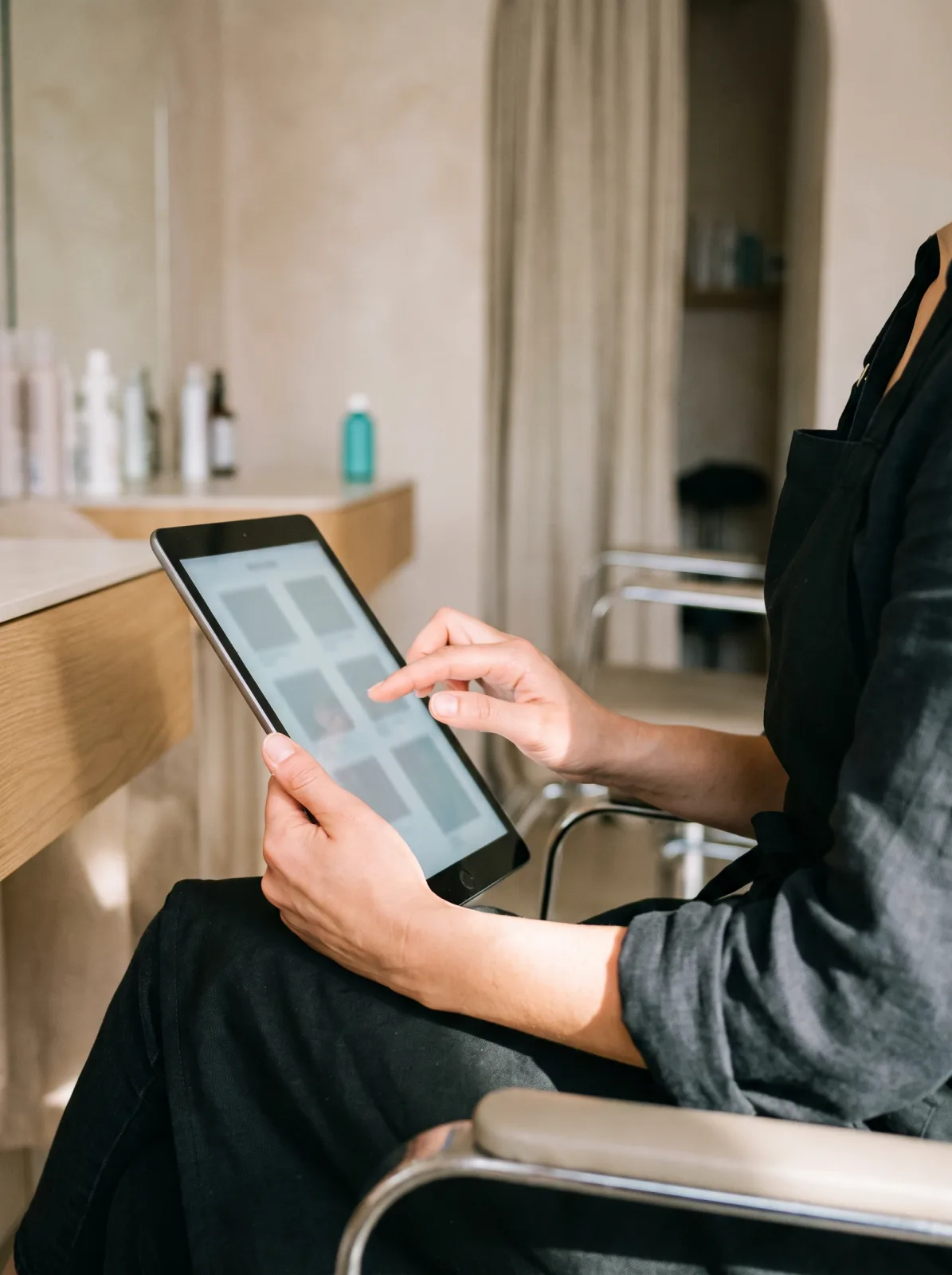 La titolare seduta in salone che consulta una scheda cliente sul tablet