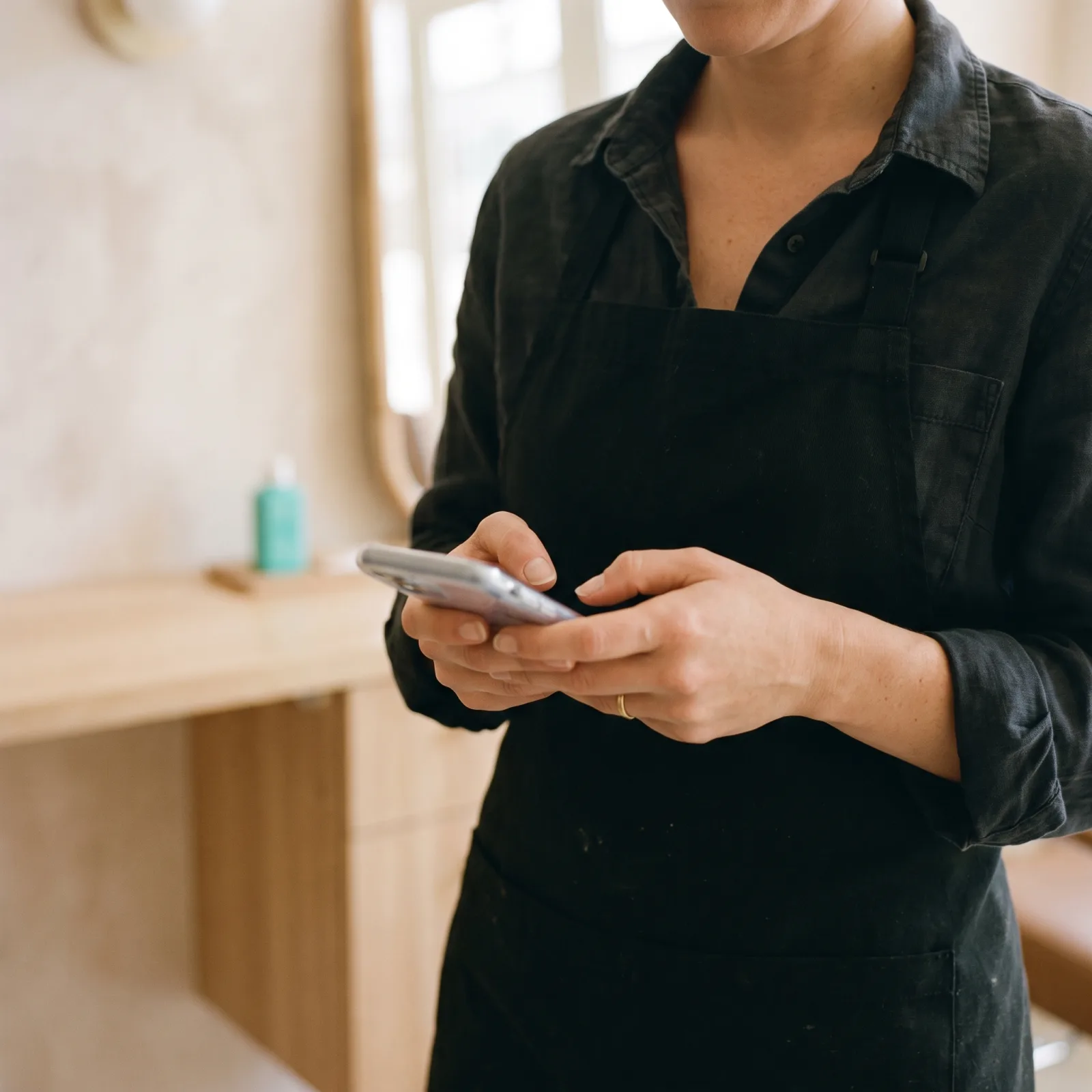 La titolare del salone che scrive un promemoria dal telefono, ripresa all’altezza del petto